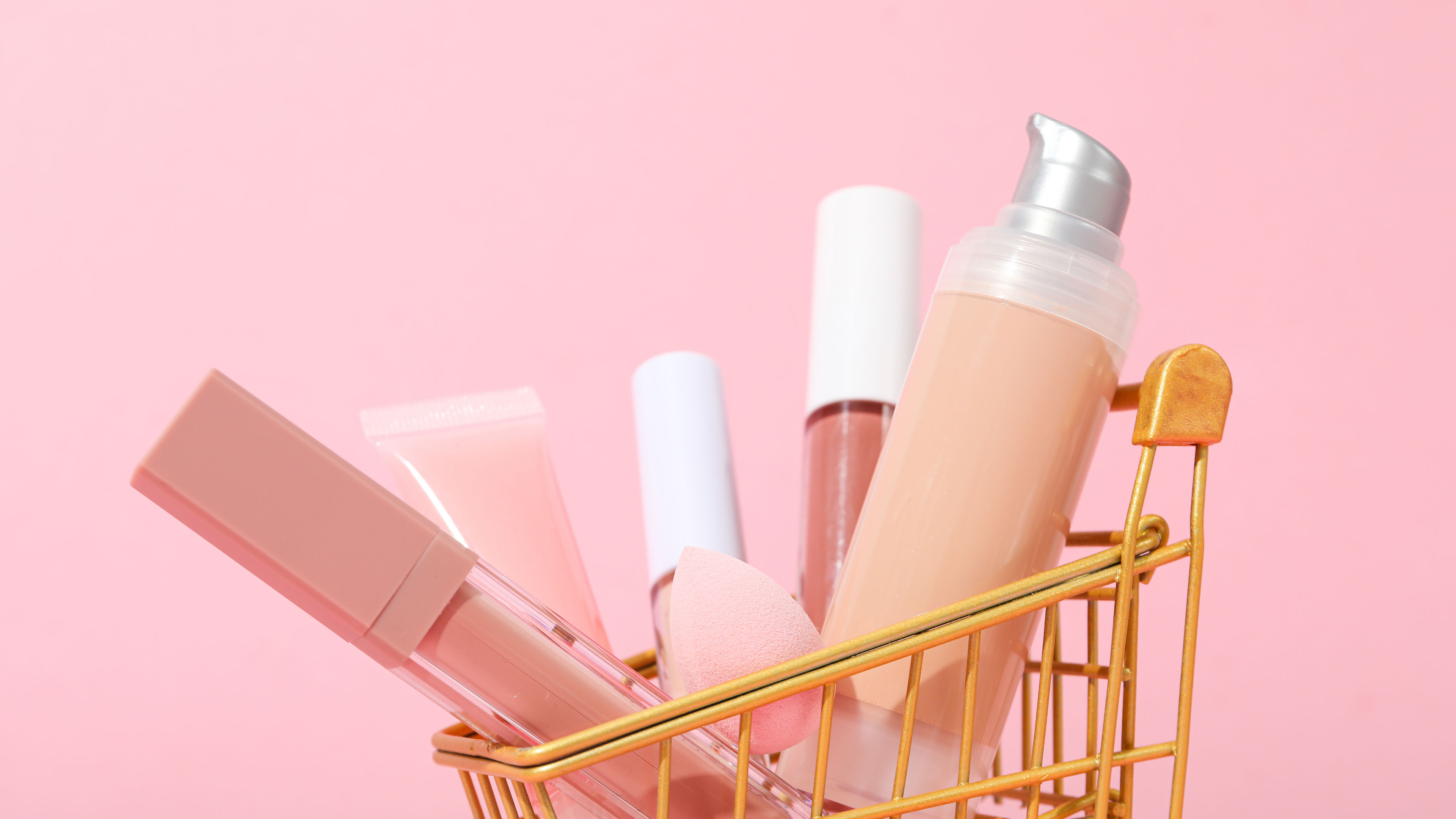 A small golden shopping basket is filled with beauty items