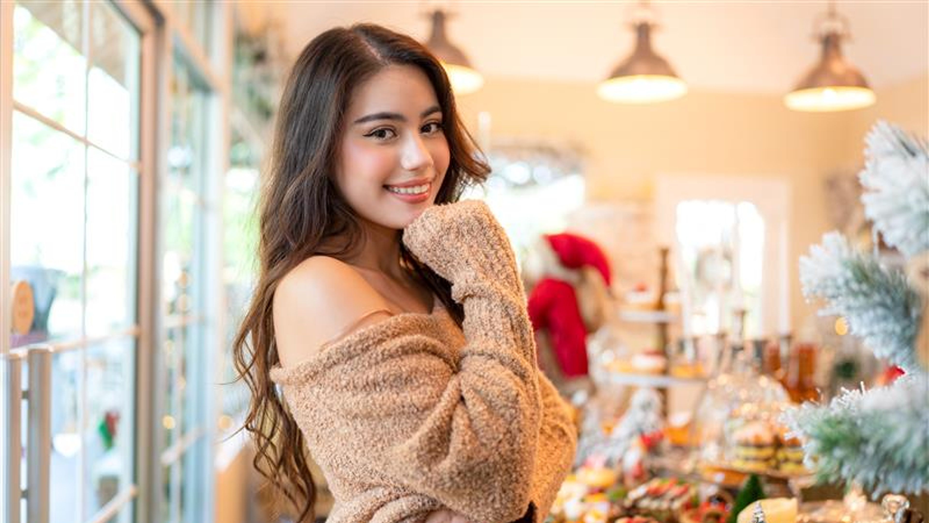 A smiling woman in a cosy shop, surrounded by festive treats and decor