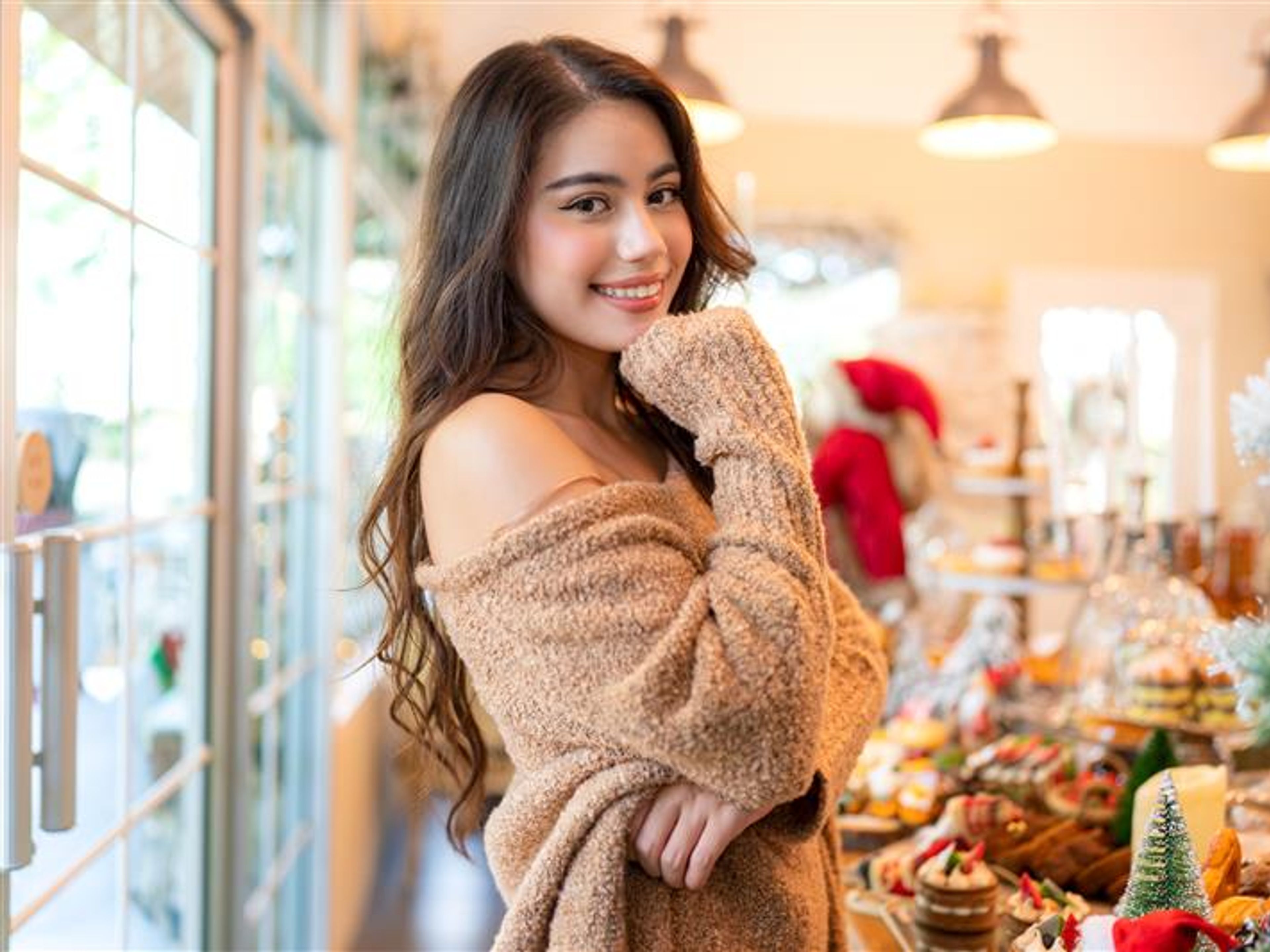 A smiling woman in a cosy shop, surrounded by festive treats and decor