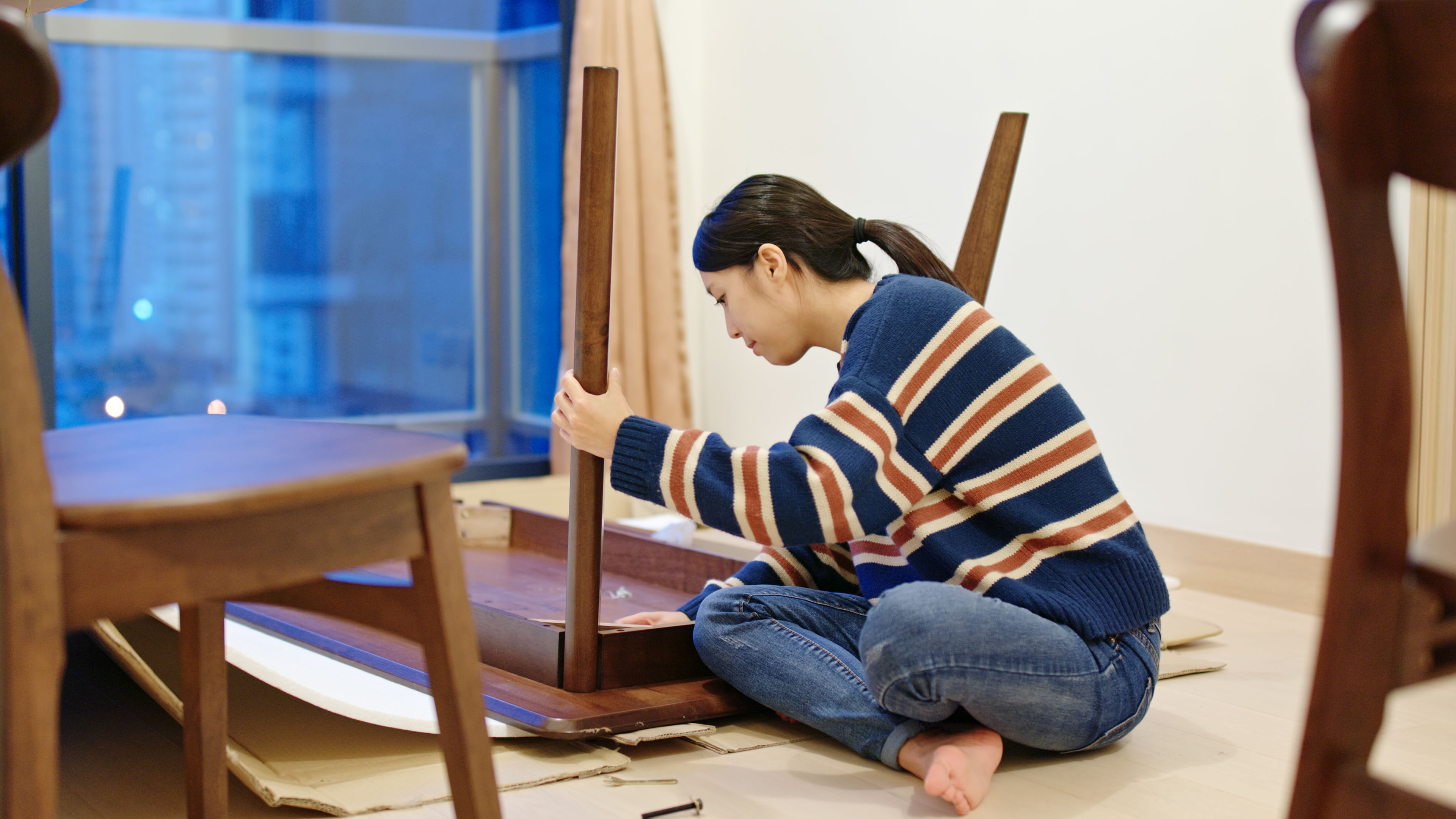 A young woman assembling a wooden table.