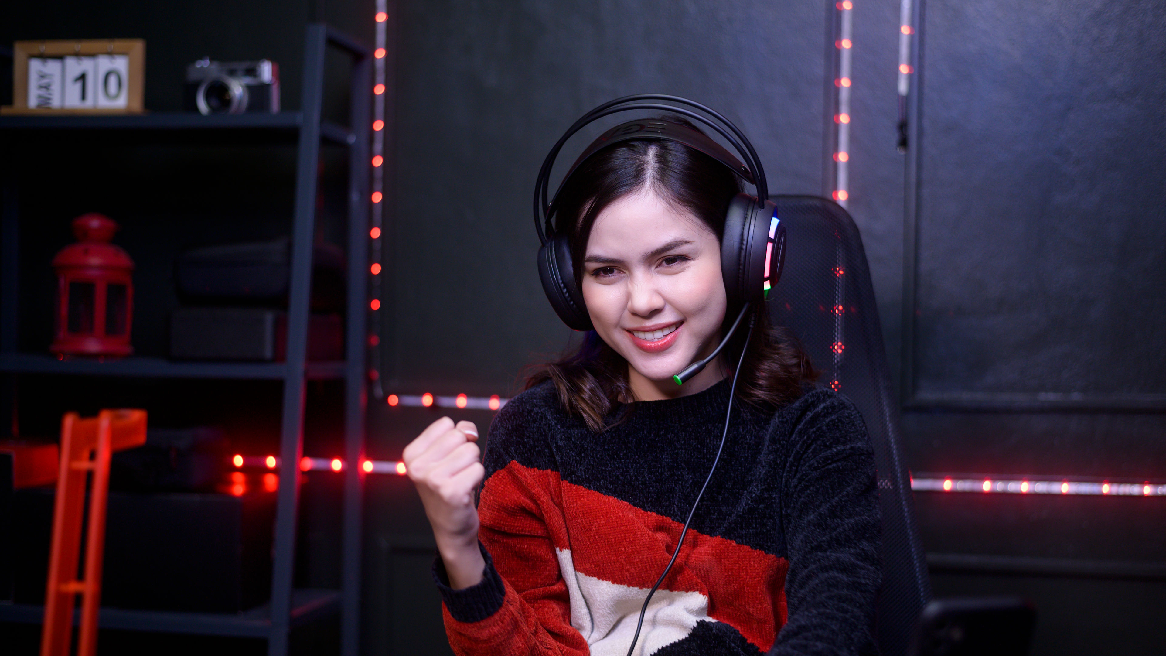 A young woman wearing a headset is sitting at a gaming desk