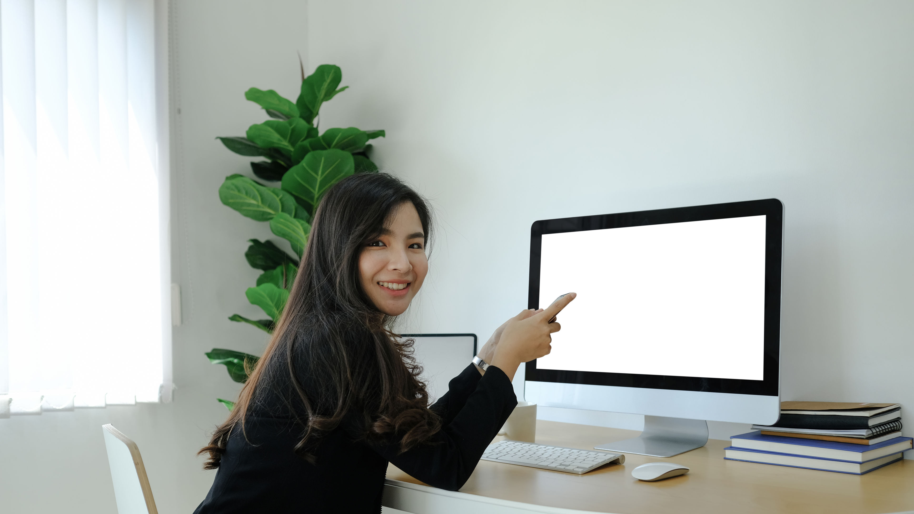 Woman sitting in front of monitor and smiling.