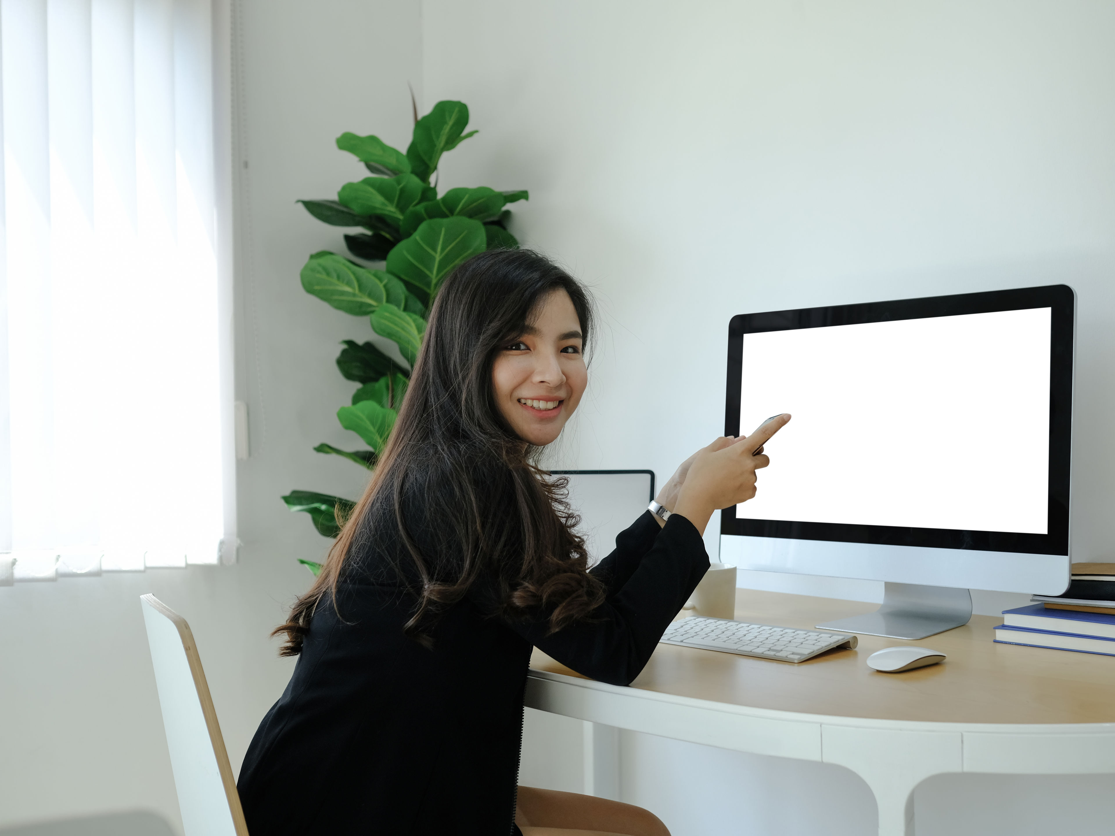 Woman sitting in front of monitor and smiling.