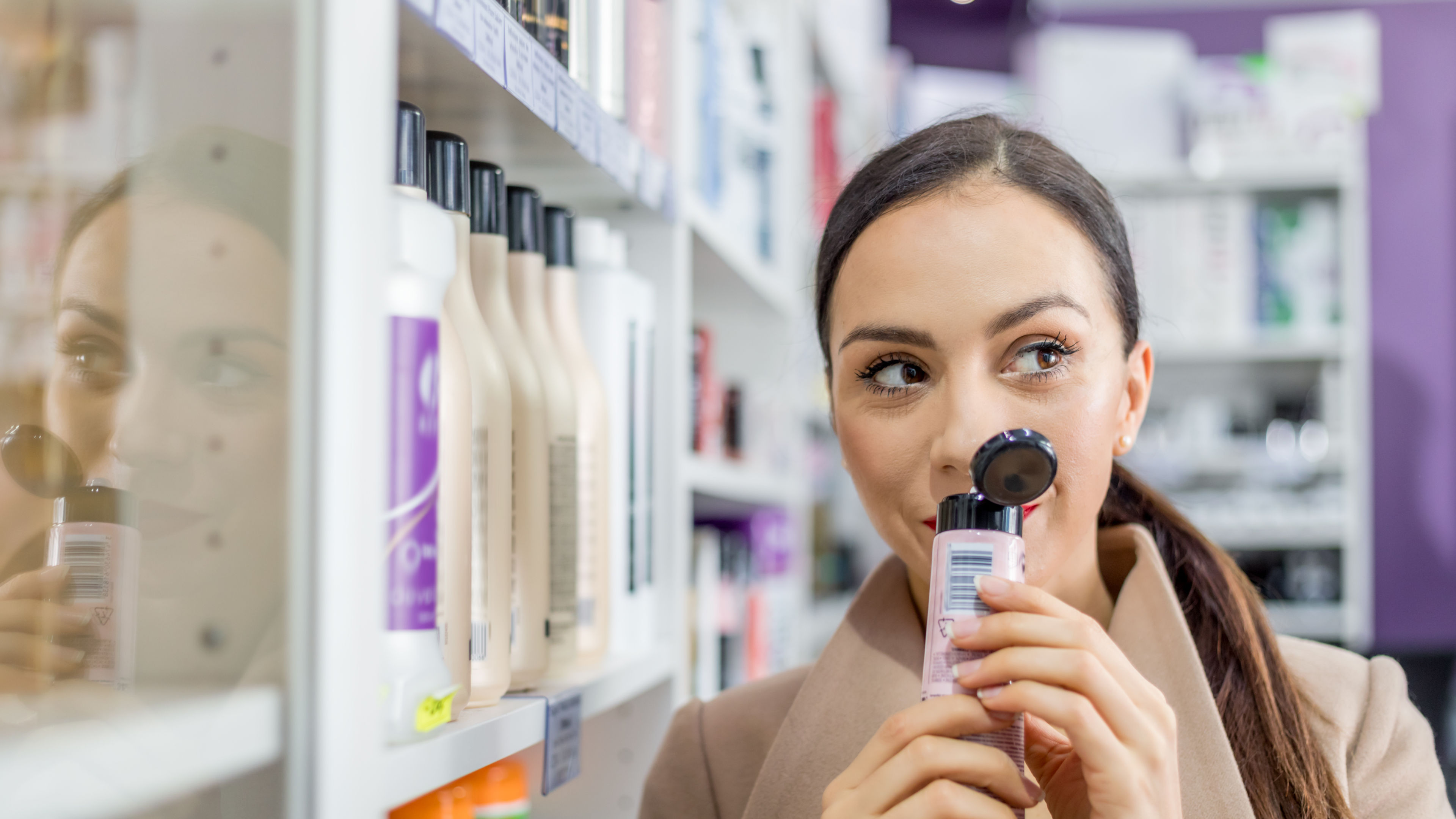 Smiling woman in cosmetic store looking for beauty skin care products.