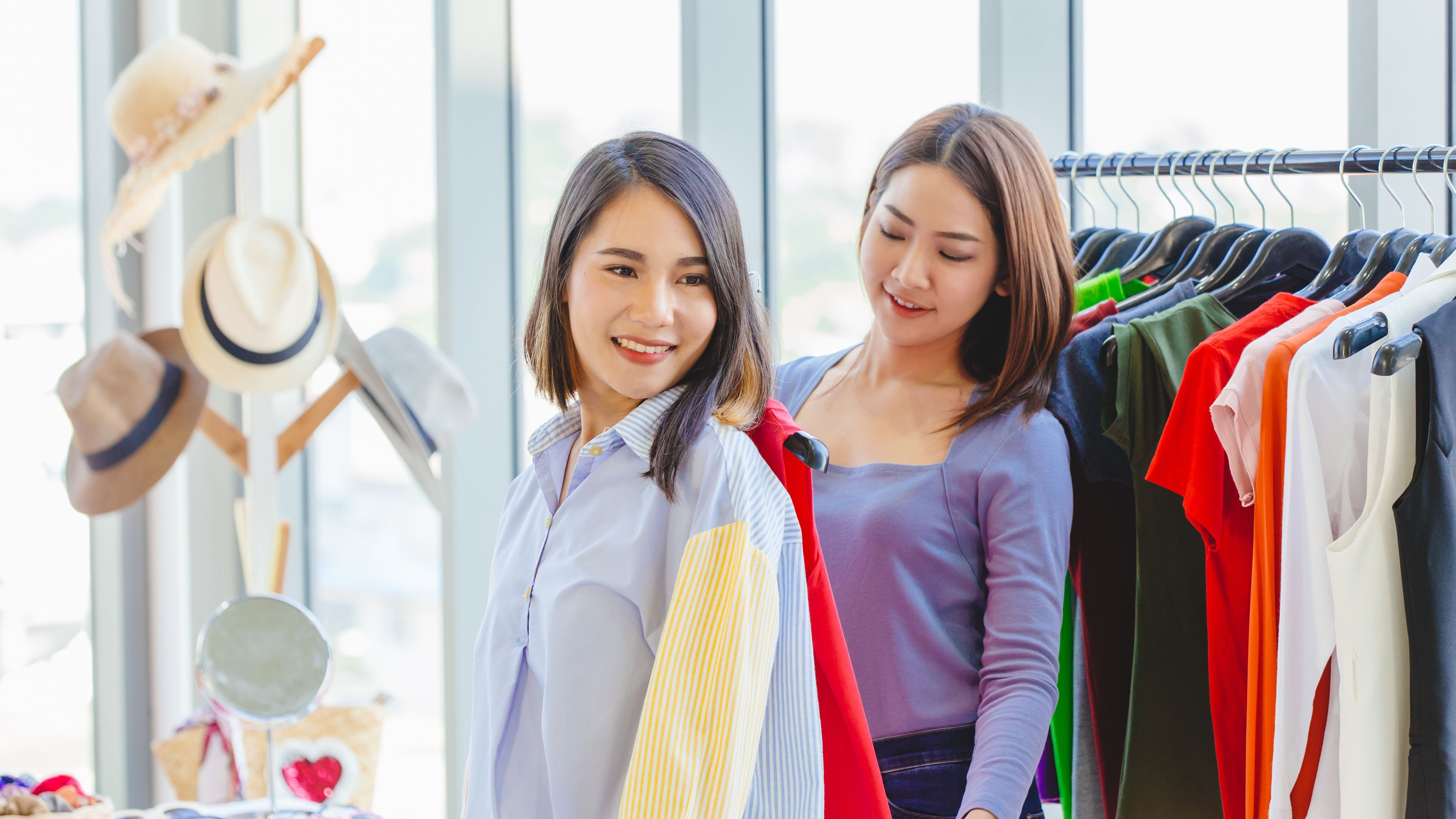 Happy women shopping with friend in fashion shop.