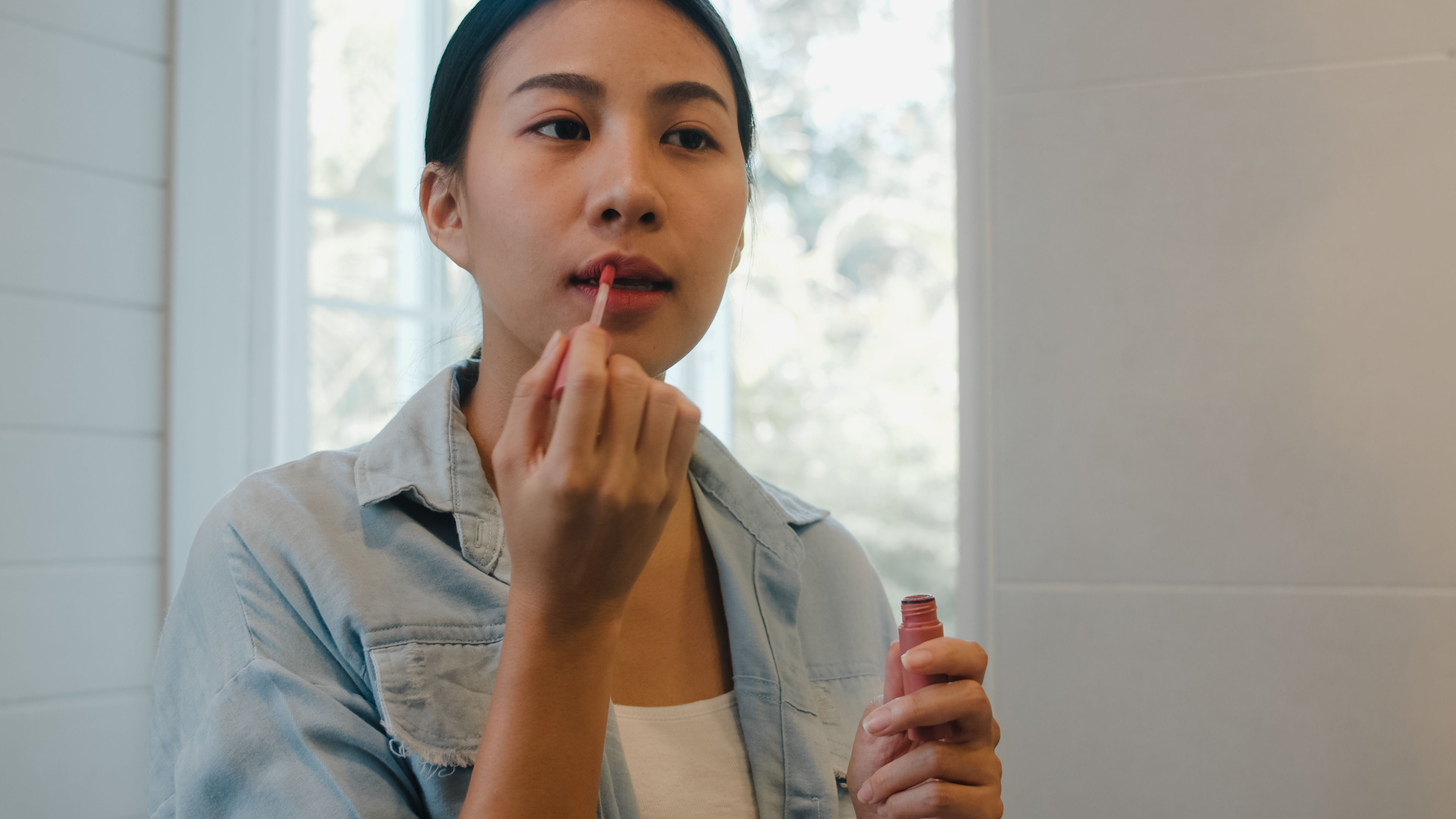 Woman applying lip gloss. 